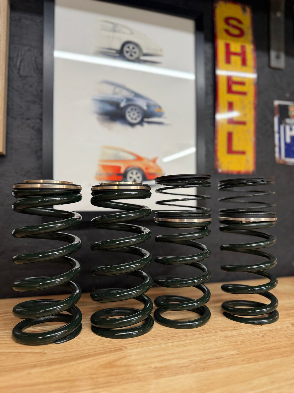 Automotive performance springs on workbench, car art and Shell sign in workshop, Eastwood Engineering