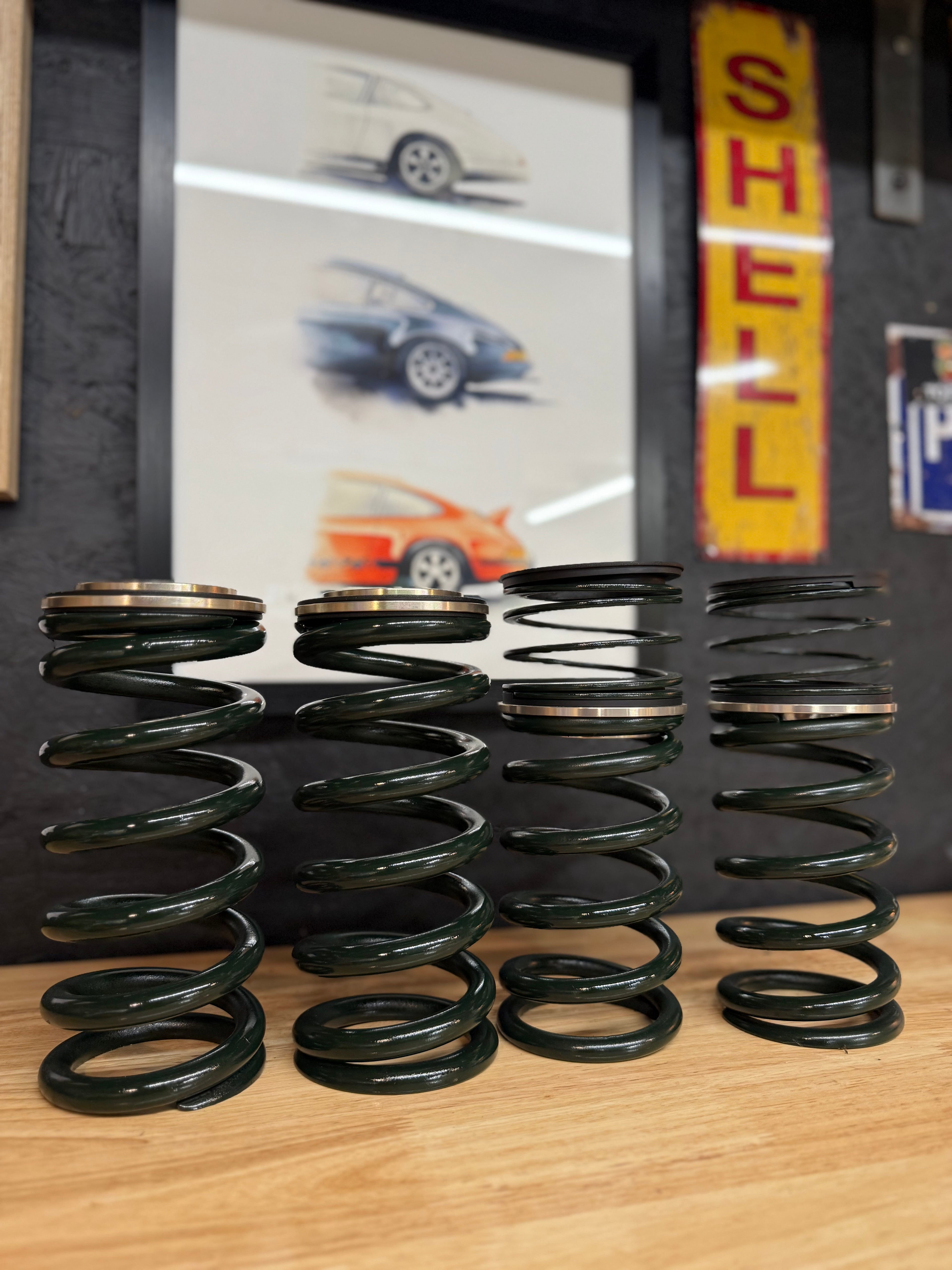 Automotive performance springs on workbench, car art and Shell sign in workshop, Eastwood Engineering