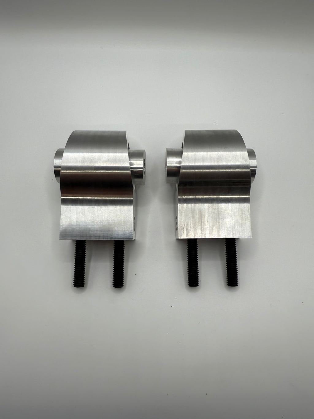 Pair of stainless steel valve controller brackets with black bolts on white background