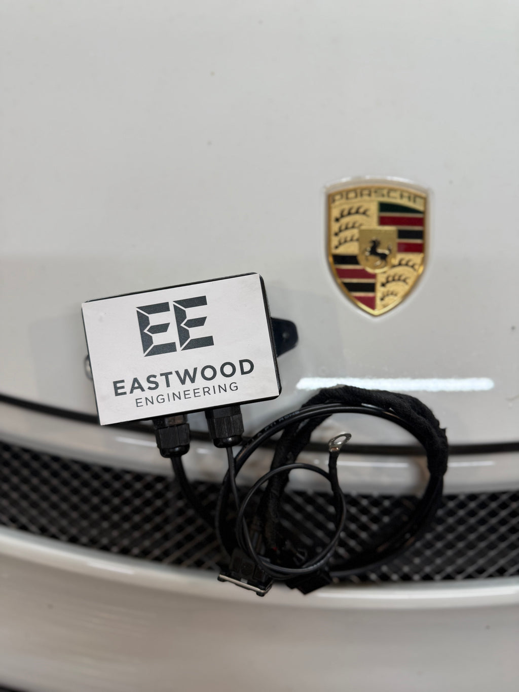 Eastwood Engineering valve controller with cables in front of Porsche badge on car grille