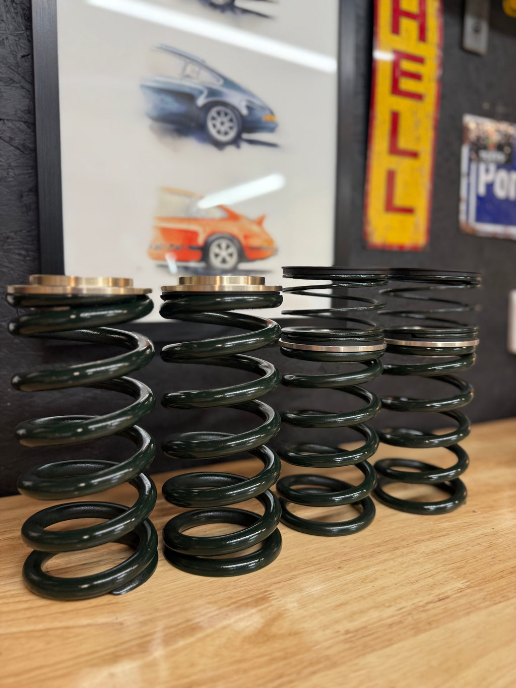 Four automotive valve springs on a wooden table, Eastwood Engineering workshop setting.